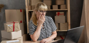 Frau besorgt am Laptop mit Versandpaketen